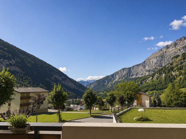 Un paisaje montañoso con cielo despejado, una zona residencial con casas y una montaña destacada al fondo.