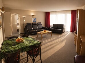 Ein Wohnzimmer mit einer Couch, einem Couchtisch und einem Essbereich mit Stühlen und Tisch.