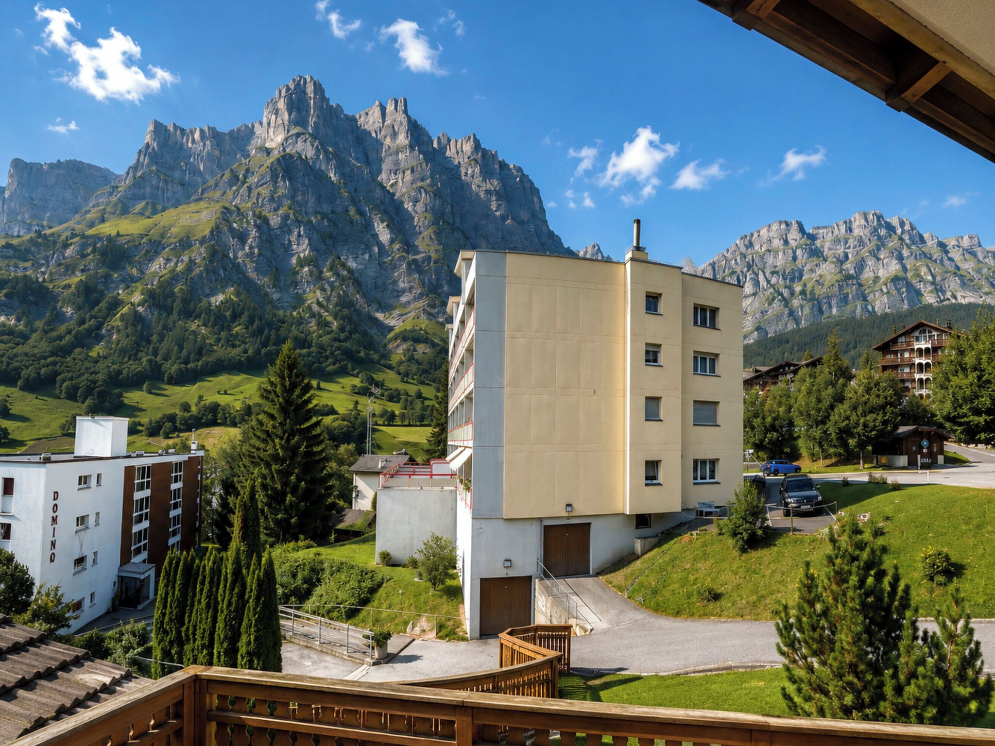 Un hotel con vista a la montaña, un estacionamiento y un pequeño edificio con un cartel.
