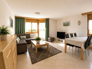 Ein modernes Wohnzimmer mit Sofa, Couchtisch, Fernseher und Essbereich.