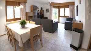 A spacious living area with a dining table, sofas, and a kitchen in the background. - Residenz Darianne Leukerbad # 5-bed apartment, Dusche und Bad, WC by Interhome (Leukerbad)