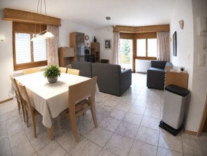 Ein geräumiger Wohnbereich mit Esstisch, Sofas und einer Küche im Hintergrund.
