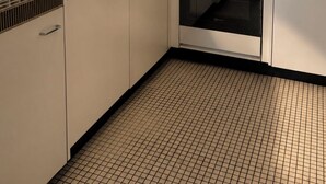 Una cocina con alacenas blancas, salpicadero de azulejos, pileta de acero inoxidable y horno empotrado.