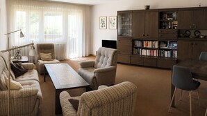 Una sala de estar con un sofá, una mesa de centro, un televisor y una estantería.