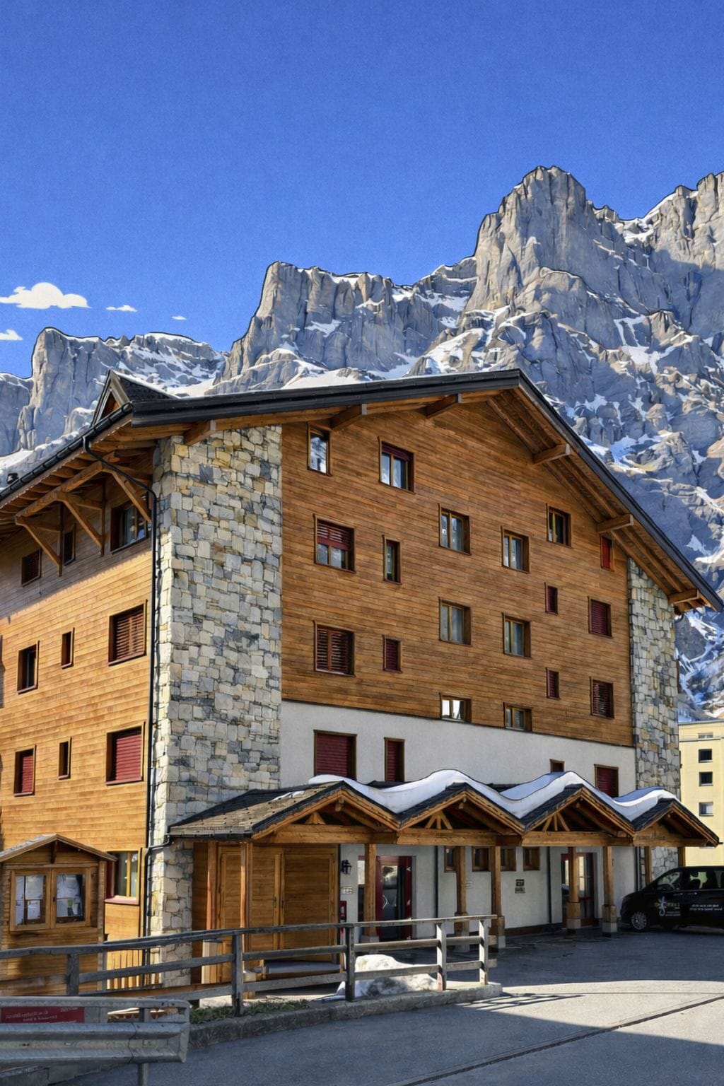 Ein mehrstöckiges Gebäude mit Stein- und Holzbauweise, zahlreichen Fenstern und einem mit Schnee bedeckten Dach.