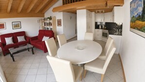 A modern interior with a dining area, red sofa, and kitchen. - Residenz Darianne Leukerbad # 4-bed apartment, Dusche, WC by Interhome (Leukerbad)