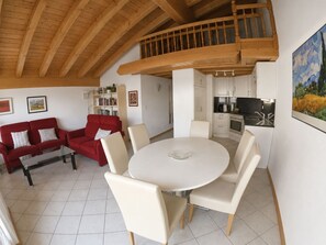 Ein modernes Interieur mit Essbereich, rotem Sofa und Küche.
