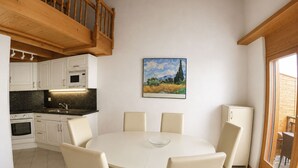 A modern kitchen with white cabinets, a dining table with chairs, and a painting on the wall. - Residenz Darianne Leukerbad # 4-bed apartment, Dusche, WC by Interhome (Leukerbad)
