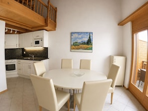 Eine moderne Küche mit weißen Schränken, einem Esstisch mit Stühlen und einem Bild an der Wand.