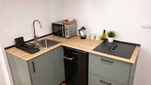 A compact kitchen with a sink, microwave, coffee maker, and a small potted plant. - Chic Madrid Stay With Terrace (Madrid)