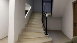A staircase with a black railing, beige carpeted steps, and a light-colored floor. - Chic Madrid Stay With Terrace (Madrid)