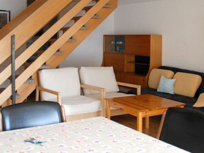 Ein modernes Wohnzimmer mit einer Holztreppe, einer Sofagarnitur, einem Couchtisch und einem Schrank.