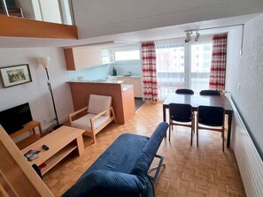 A compact living space with a sofa, a small table, a kitchenette, and a dining area with chairs. - Fortuna 307 # 5-bed apartment, Dusche, WC 5-Bettwohnung, Dusche, WC by Interhome (Leukerbad)