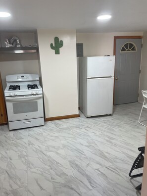 A kitchen with a gas stove, a white refrigerator, and a door with a window.