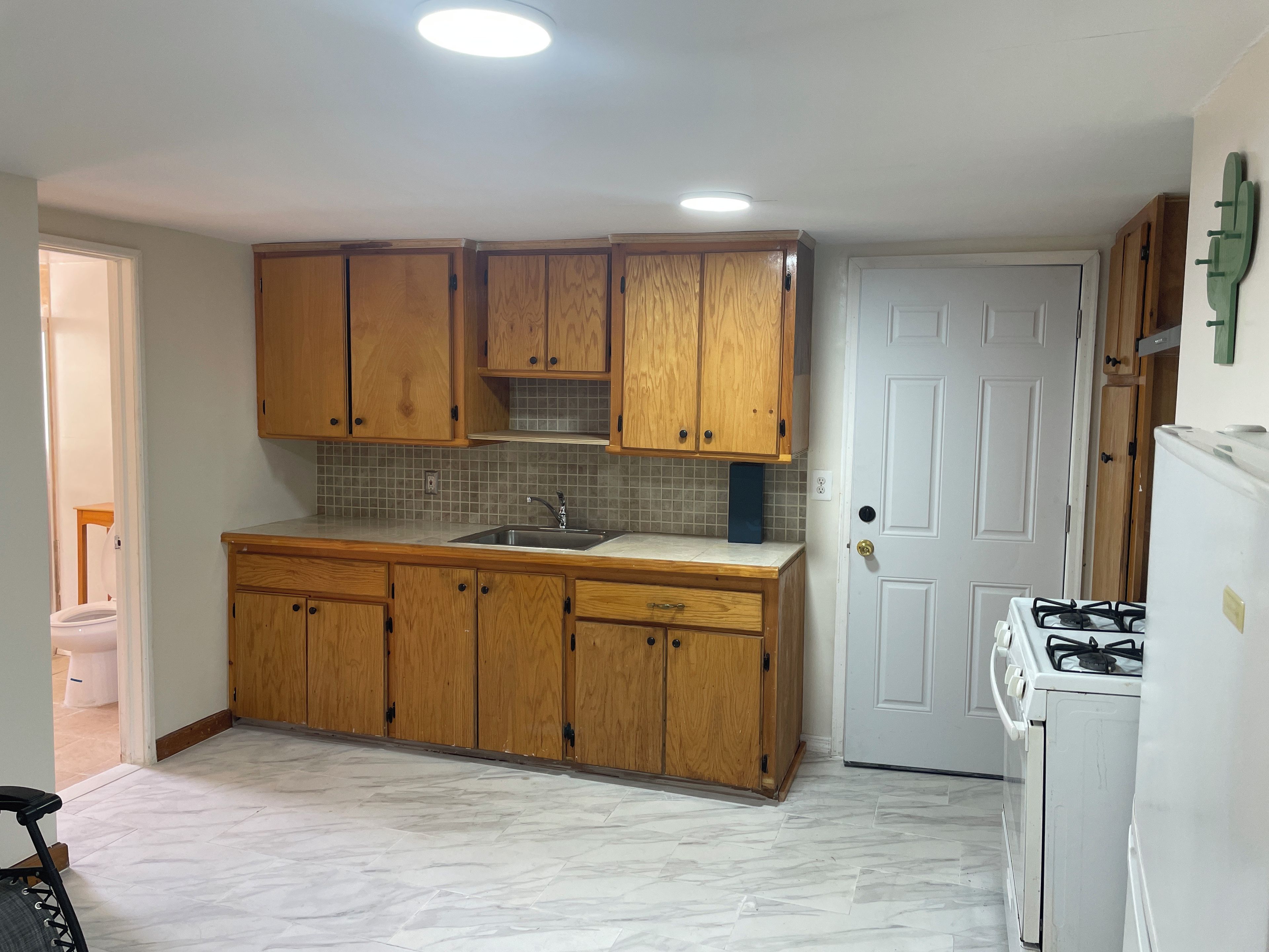 A kitchen with wooden cabinets, a sink, a stove, and a door.