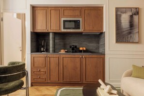 A compact kitchen with wooden cabinets, a built-in microwave, and a coffee maker. - Stunning A/C Flat -1bdr/4p- Saint-germain-des-pres (Paris)