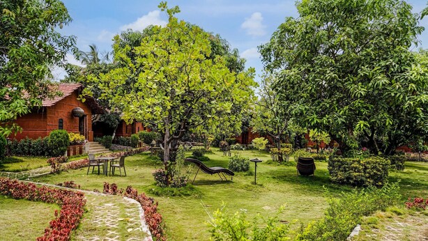 A garden with a red-roofed building, a paved pathway, and a seating area.