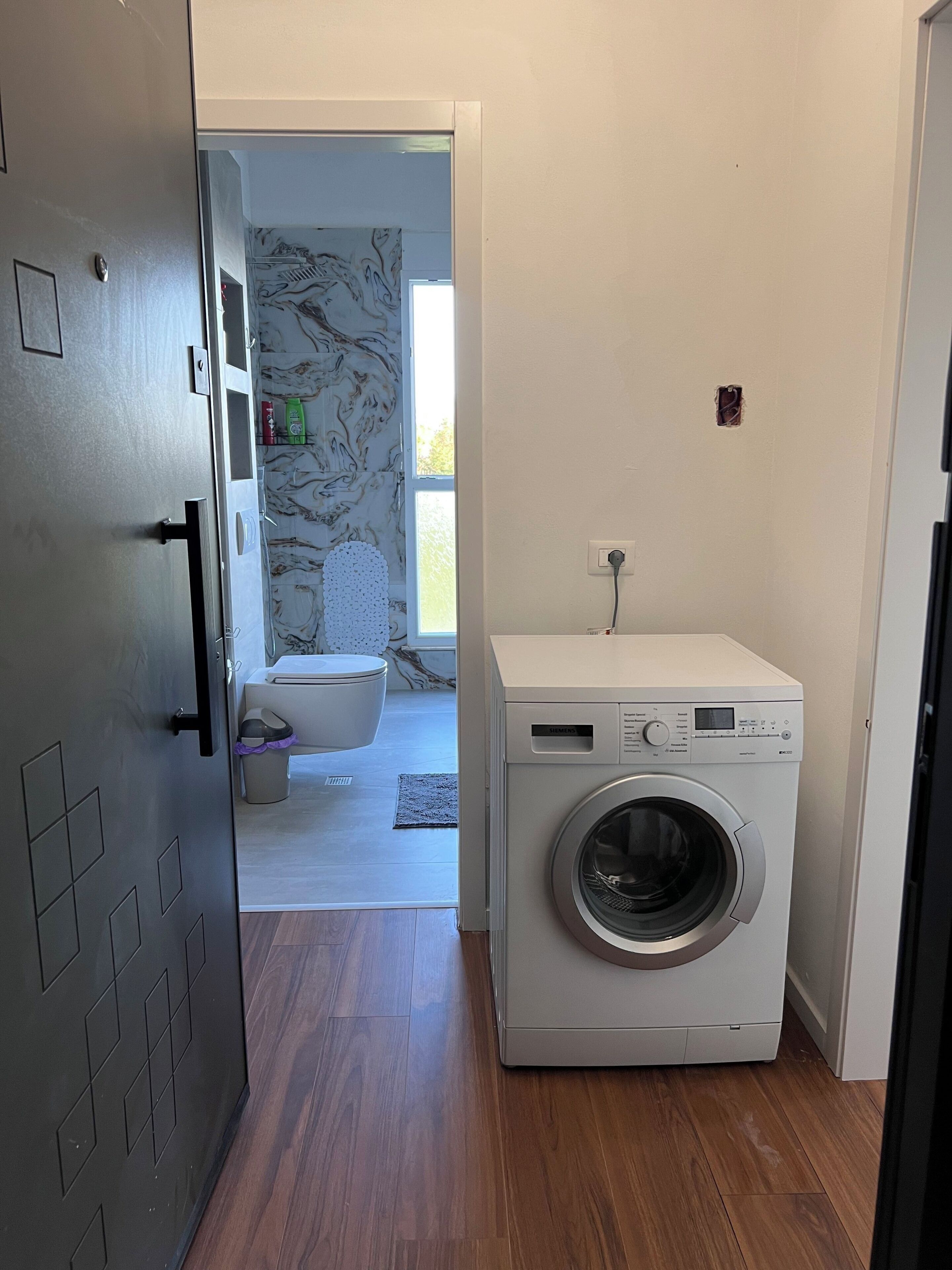 Une buanderie équipée d’un lave-linge, de toilettes et d’une porte donnant accès à une salle de bain.