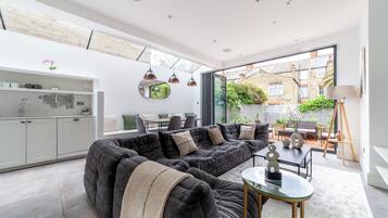 A modern living room with a sectional sofa, a glass coffee table, and a dining area with a table and chairs.