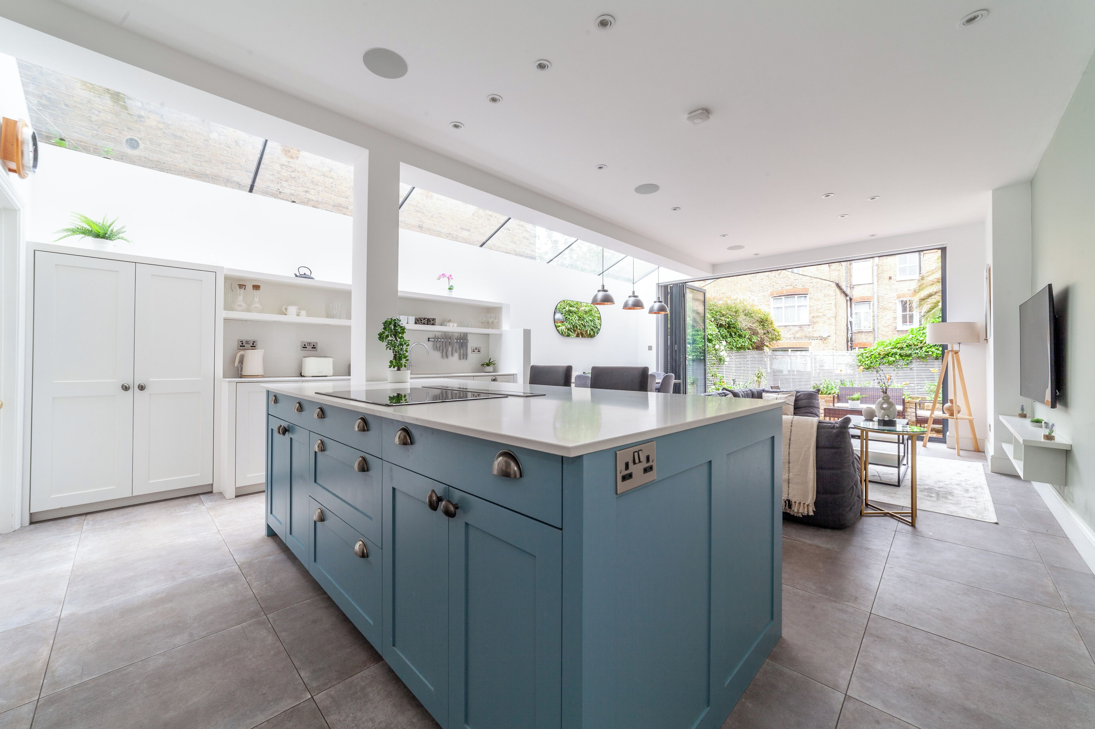 A modern kitchen with a large island, white cabinets, and a view to the outside.