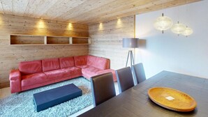A modern interior with a wooden ceiling, a red leather sofa, a dining table with chairs, and pendant lighting. - Apartment Skyline 406 by Interhome (St. Moritz)