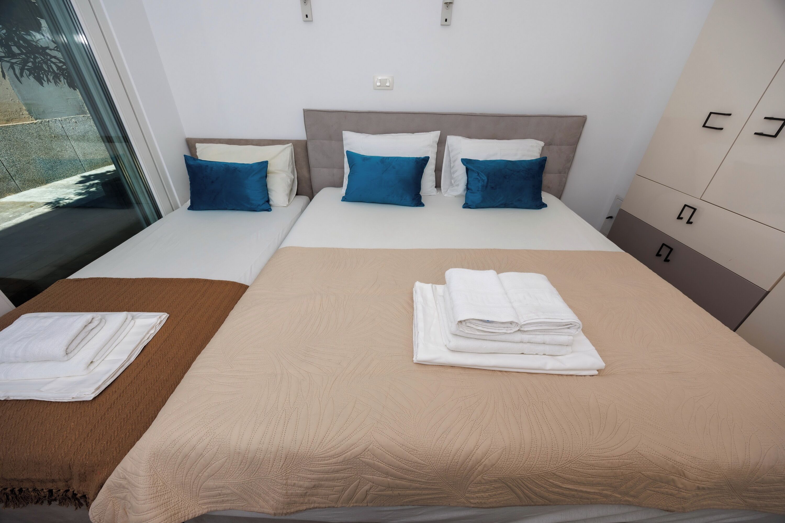 Quarto de hotel com uma cama, mesa de cabeceira, guarda-roupa e janela.