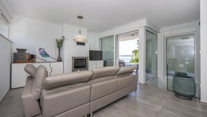 Un salon moderne comprenant un canapé, un téléviseur à écran plat et un coin repas avec une table et des chaises.