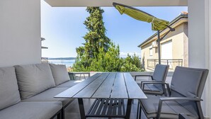 Un espace extérieur aménagé avec une table et des chaises, offrant une vue sur une étendue d’eau et un arbre.