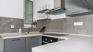 Une cuisine moderne dotée d’un lave-vaisselle encastré, d’une fenêtre avec stores et d’un plan de travail agrémenté d’une plante et d’un porte-couteaux.