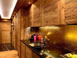Eine moderne Küche mit Holzvertäfelung, einer schwarzen Arbeitsplatte und Edelstahlgeräten.