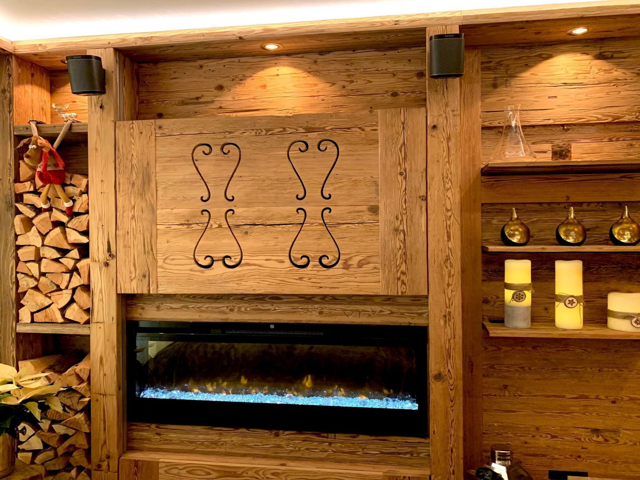 A wooden interior with a fireplace, a wall-mounted decorative metal piece, and a shelf with candles.