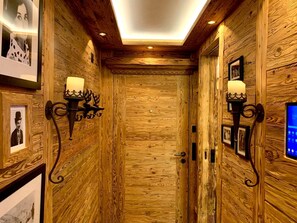 Ein Holzboden-Flur mit einer Tür, Wandleuchten und gerahmten Bildern.