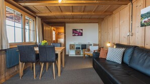 Interior de madera con comedor, sofá y estante fijado a la pared.