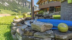 Una casa moderna con un patio de piedra, un jacuzzi y vistas a la montaña.