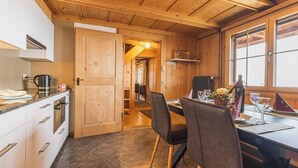 Un interior de madera con cocina, mesa de comedor, sillas y una ventana.