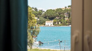 Vista per una finestra d'una zona costanera amb edificis damunt d'una collada, un cos d'aigua i un moll amb barques.