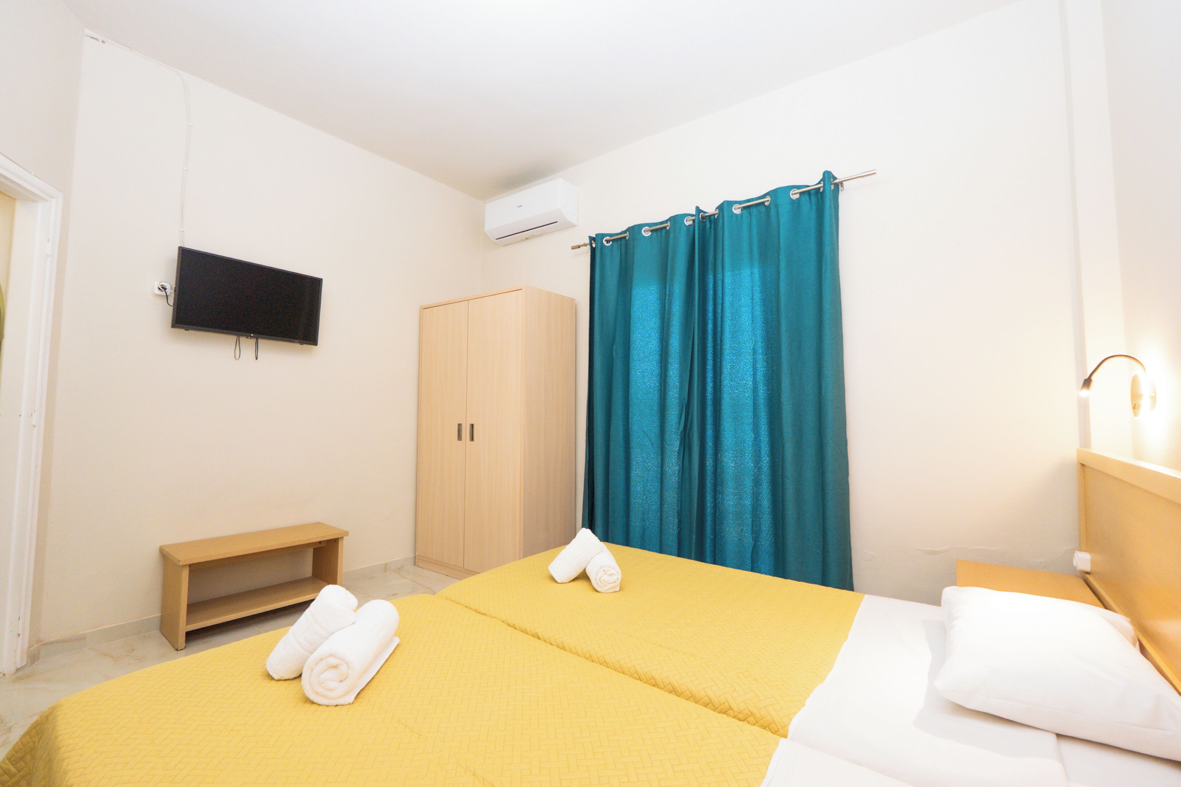 A hotel room with a bed, a TV, a wardrobe, and a shower curtain.