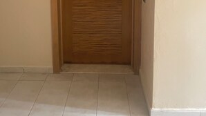 A closed wooden door with a metal handle, a tiled floor, and plain walls. - Design Apt @ Blanca Beach: Private Beach & Pool (Sidi Rahal)