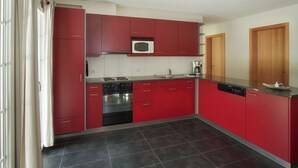 Eine moderne Küche mit roten Schränken, einem schwarzen Backofen und einer Mikrowelle.