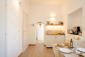 Eine kleine Küche mit weißen Schränken, einem Esstisch für zwei Personen und einer Arbeitsplatte mit einem Toaster.