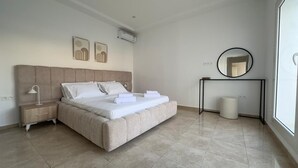 Un dormitorio con cama, mesitas de noche, un espejo y obras de arte en la pared.