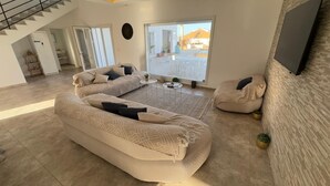 Amplia sala de estar con un sofá modular grande, una mesa de centro y un puerta corrediza de vidrio que da a un patio exterior.
