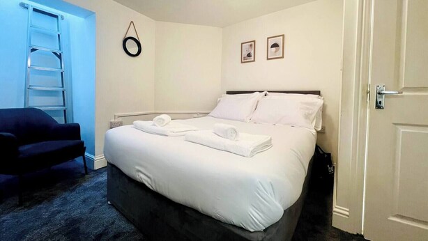 Une chambre d’hôtel avec un lit, une chaise, une échelle et une porte.
