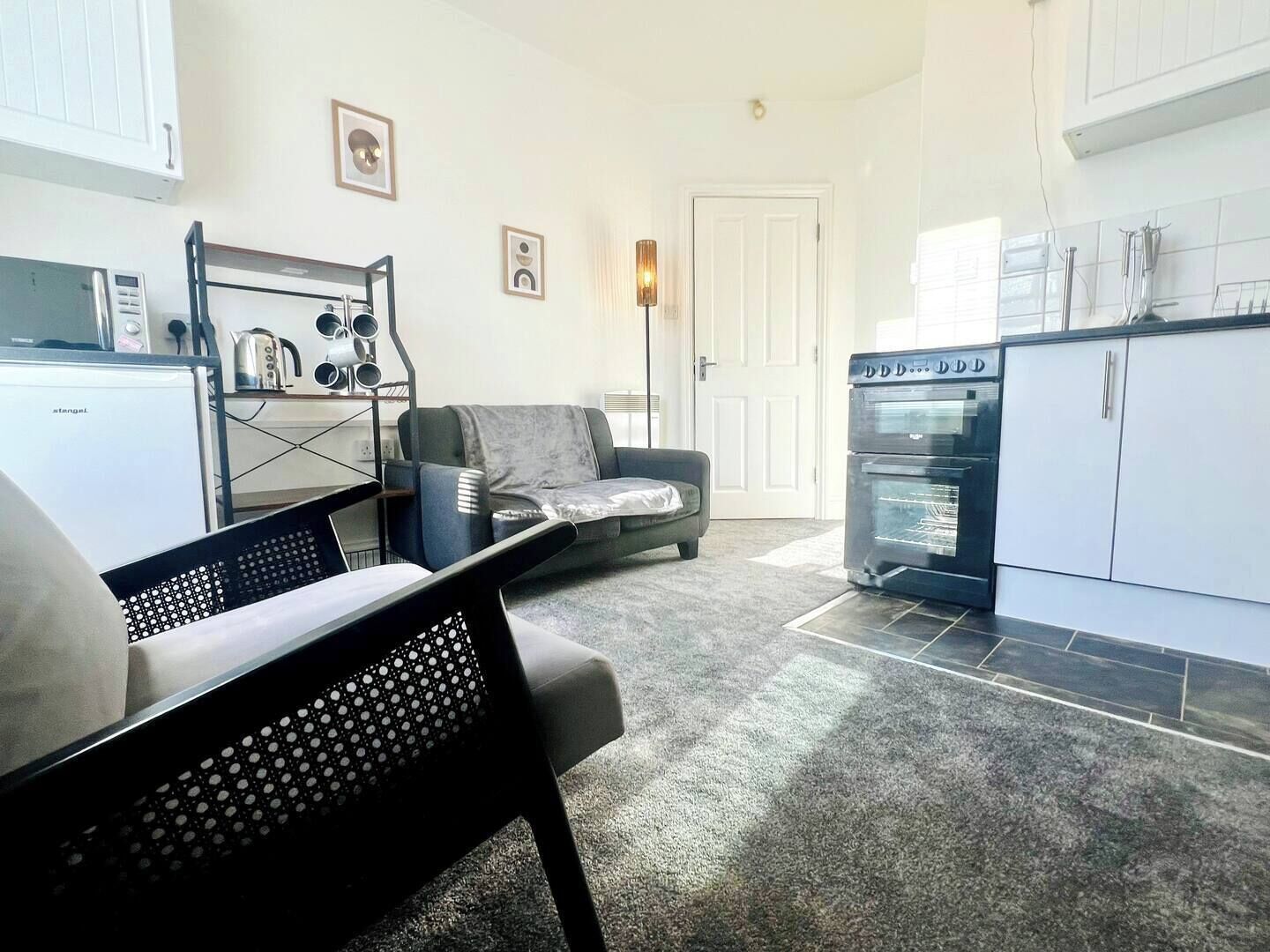 A compact living space with a kitchenette, a sofa, a dining table, and a chair.