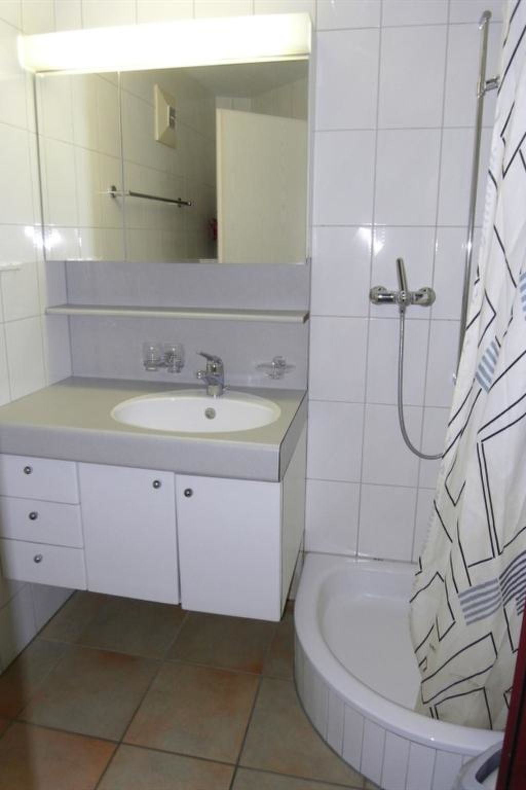 A bathroom with a white sink, mirror, and shower.
