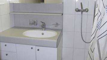 A bathroom with a white sink, mirror, and shower.