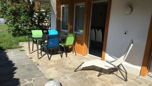 A patio with stone flooring, outdoor furniture, and a small rock garden with flowers. - Schwizi's Holiday Apartments Appartement/Fewo, Dusche, WC, 1 Schlafraum No. 02 by Interhome (Ringgenberg)