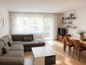 A modern living room with a sectional sofa, a dining table with chairs, a flat-screen TV, and a kitchen area with wooden cabinets and a countertop. - Majesta Leukerbad # 6-bed apartment, Dusche und Bad, WC by Interhome (Leukerbad)