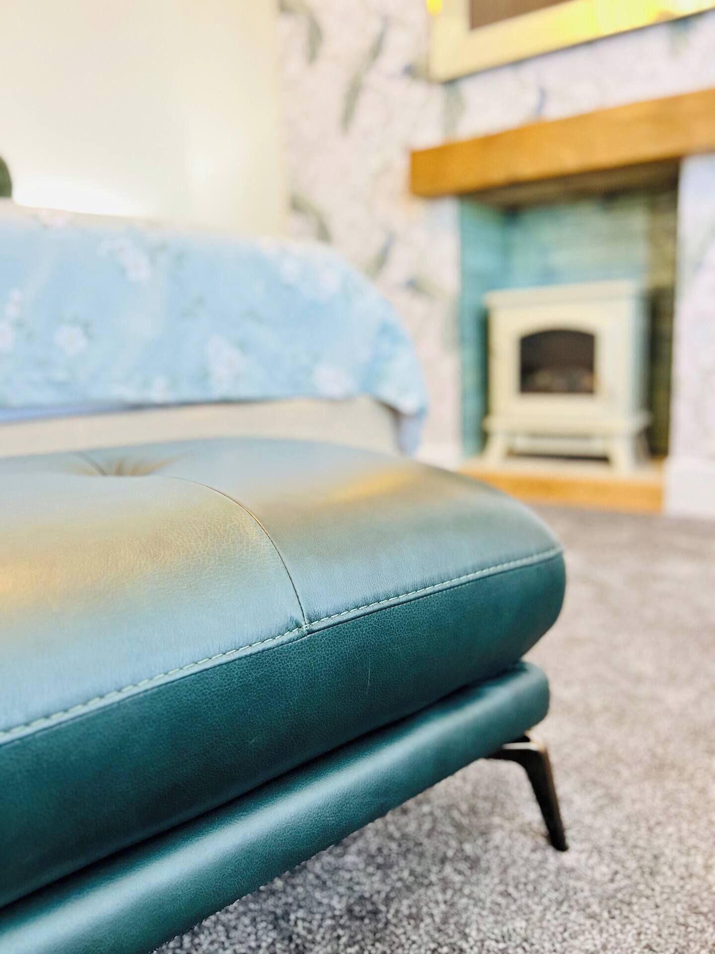Ein blaugrünes Sofa, ein Holzkopfende und ein Kamin im Hintergrund.