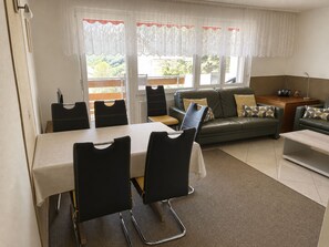 A compact living space with a dining table, chairs, a sofa, and a small TV. - Majesta Leukerbad # 6-bed apartment, Dusche oder Bad, WC by Interhome (Leukerbad)
